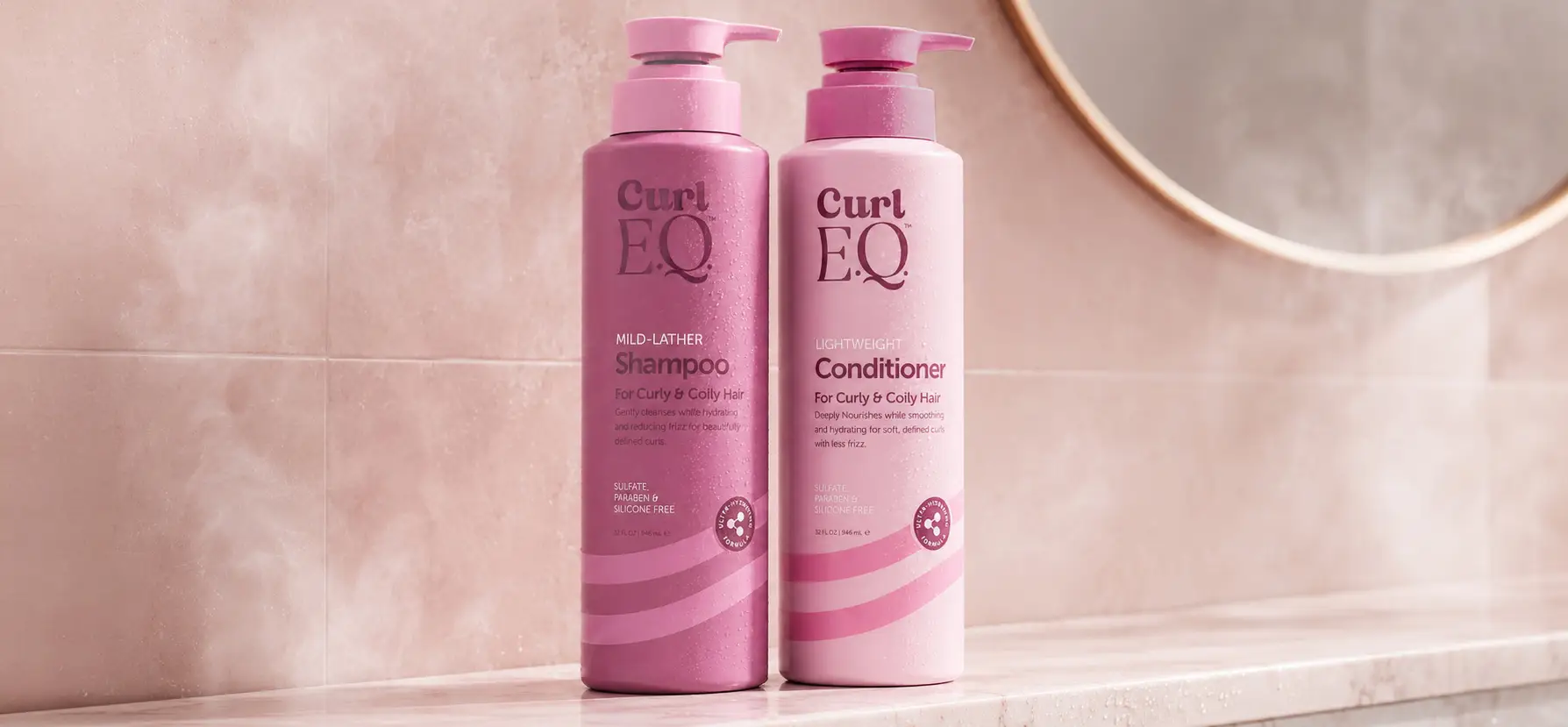 Read the article: What Makes a Good Formula for Curly Hair? Image: CurlEQ shampoo and conditioner bottles displayed on a bathroom counter beside a mirror